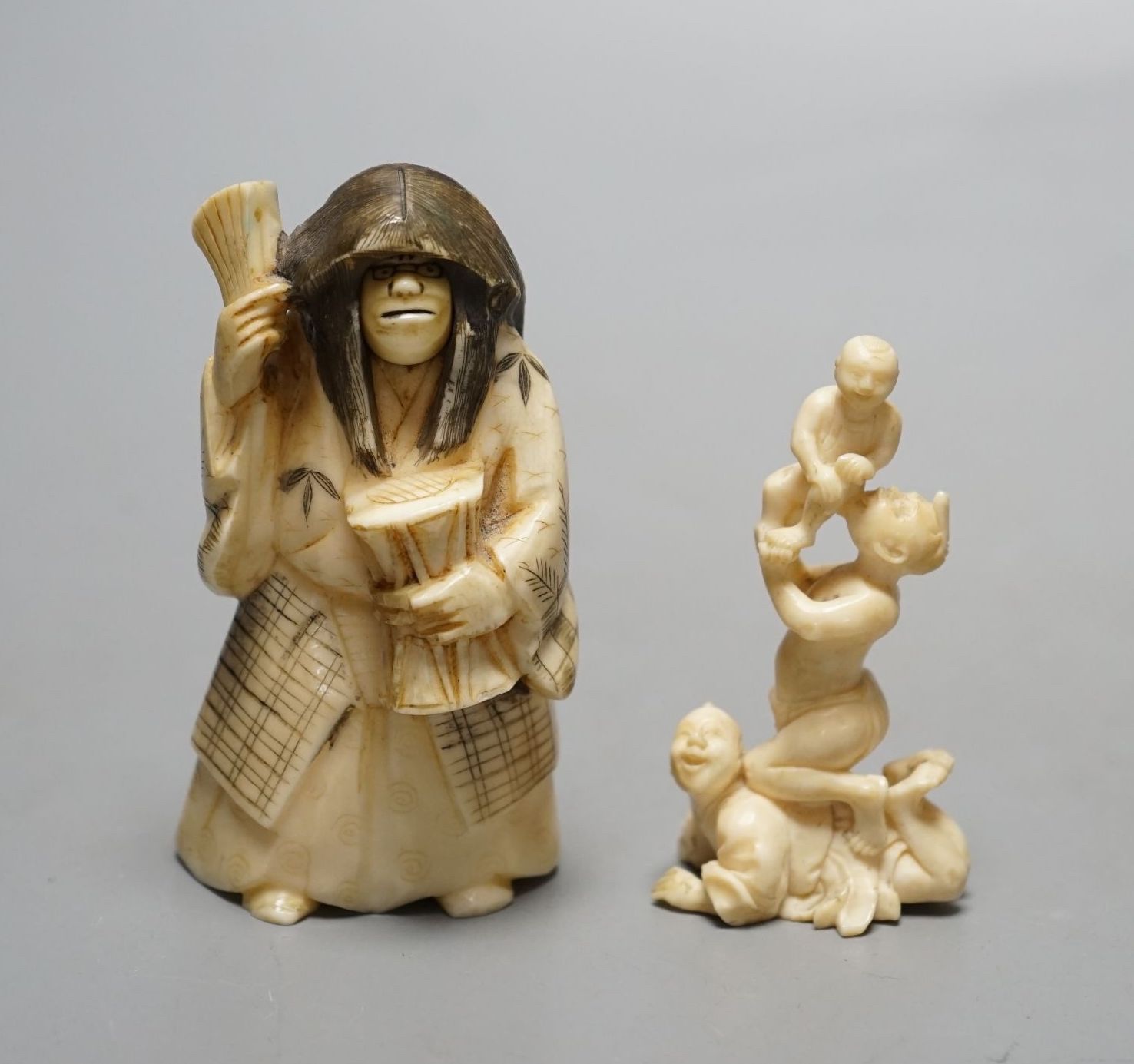 A Japanese face changer, early 20th century, a small okimono of acrobats, Meiji period and an ivory paper knife with lacquer decoration, face changer 8 cms high.